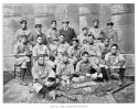 Members of the champion 1899 baseball team pose for a photo wearing their uniforms in three rows, with mitts, bats, and catcher's gear spread out before them