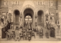 Black and white photo of the Junior Yard posing on the north steps of Healy Hall, showing approximately sixty students sitting or standing on the stairs with two Jesuits on either side 