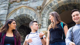 Four students joke with each other while descending the stairs at Healy Hall