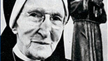 Sister Rosaline Doyle, dressed in a habit, with a statue of Saint Francis in the background