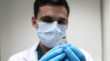 Army Specialist Angel Laureano holds a vial of the COVID-19 vaccine
