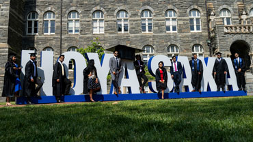Graduates in front of the Hoya Saxa sign on Healy Lawn