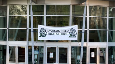 Entry to Jackson-Reed High School with a temporary banner showing the new name