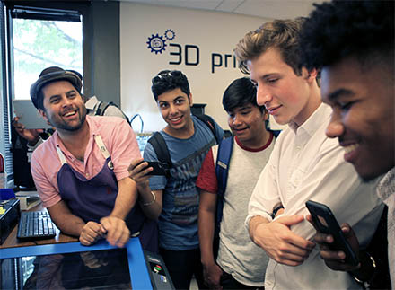 Students and the Maker Hub manager gather around the laser cutter in a training session