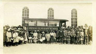 Students and faculty of St. Peter Claver’s School photographed in front of the first bus used by the parochial school in 1927, two years after its establishment.