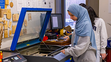 a woman standing next to the laser cutter