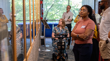 A young Black woman and others view a library exhibit.