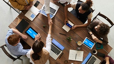 A diverse group of workers meet around a table.