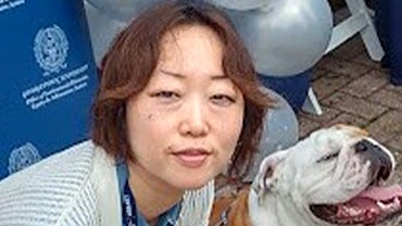 A potrait of Saori Pustejovsky, a Japanese woman, posing with Jack the Bulldog.