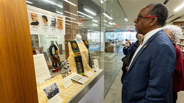 Reynold Verret, a middle-aged Black man, looks at an exhibit of materials related to Xavier University's Institute for Black Catholic Studies in Lauinger Library.