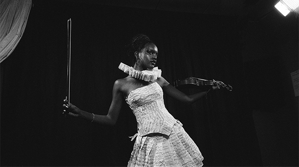 black and white photo of a black woman in a white dress playing the violin