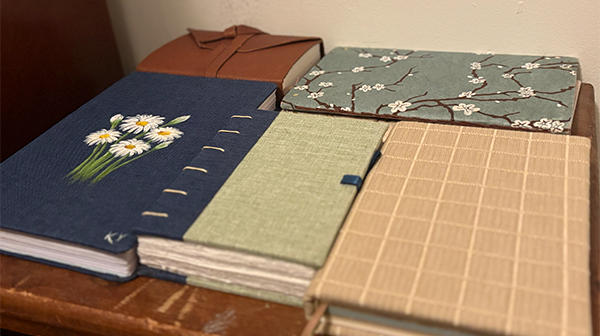five handmade journals of different sizes and colors sit on a table
