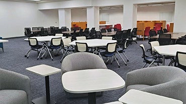 The new graduate lounge in the Blommer Science Library, showing comfy chairs in the front and a row of study tables in the back