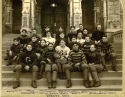 a black and white photograph of the football Team of 1900, sitting on the steps of healy hall.