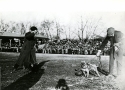 a black and white photograph of the Georgetown and University of Virginia mascots meeting on Georgetown’s athletic field before the November 18, 1911 game. the mascots, both dogs, are each held on a leash by a man. The Virginia mascot stands on the left of the image and the georgetown mascot is on the right, next to a football. 