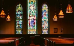 Church sanctuary with pews and three large stained glass windows