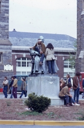 Color photograph of protesters standing on the statue of John Carroll