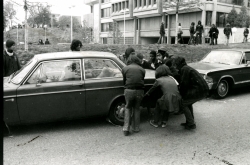 Black and white photograph of protesters trying to move a car