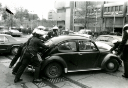 Black and white photograph of police pushing a car out of a road