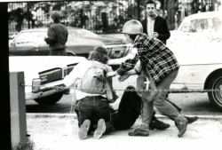 Black and white photograph of two student medics treating an injured protester