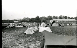 Black and white photograph of protesters tents on the athletic field, with McDonough Gymnasium in the background