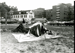Black and white photograph of protesters tents on the athletic field, with New South dormitory in the background