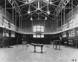 Black and white photograph of the interior of Ryan Gym with sports equipment including a pommel horse, parallel bars and rings