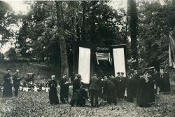 Black and white panoramic photograph showing students in graduation robes planting trees
