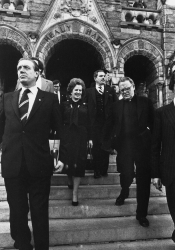 Black and white photograph of a smiling Margaret Thatcher walking down the Healy steps carrying a handbag