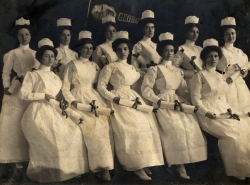 Black and white photograph of 11 graduating nursing students holding diplomas