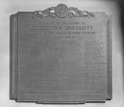 Black and white photograph of bronze plaque with four columns of names of GU students who died in WWII
