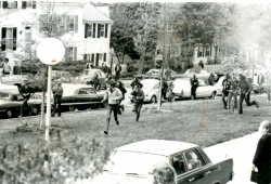 lack and white photograph showing students running away from tear gas