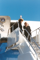 Albright and Clinton wave from the top of boarding stairs as they depart for China