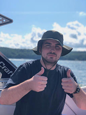 Ryan Mannion on a boat giving two thumbs up. 