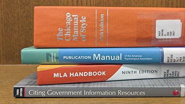 A stack of books, including the Chicago Manual of Style, APA Publication Manual, and the MLA Handbook