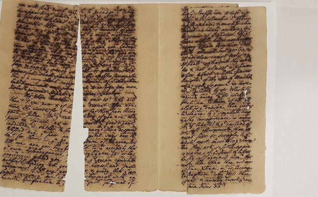 two leaves of a handwritten 1761 sermon with iron gall ink corrosion and split and with leaves split in half vertically