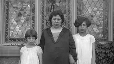 A woman and two children stand in front of a stained glass window
