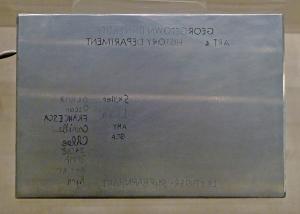 An metal etching plate has a list of names and "Georgetown University Art and Art History Department" inscribed backwards on it.