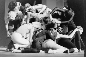 Black and white photo of a group of dancers intertwined and leaning over each other on stage.