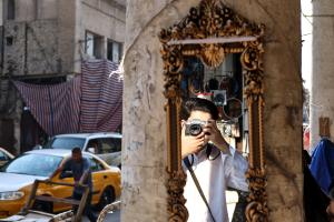 Photograph of a man on a street in Baghdad taking a photo 