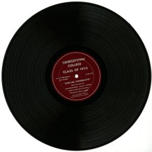 Image of a vinyl record with a maroon colored label. The Text on the label reads "Georgetown College Class of 1952. Kiss Me, Tondelayo. Music and Lyrics by John Reid Broderick and Francis X. Critchlow. Book by Malcolm M. Brennan. Directed by Mark A. Hogan. Copyrighted May 7, 1952 by Brennan, Broderick, and Critchlow."