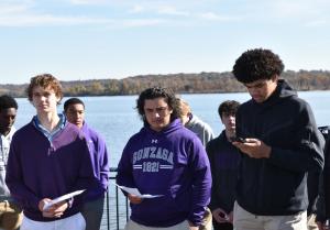 Three students wearing Gonzaga colors reading by the Potomac River