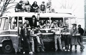 Members of GUTS posed in front of, in, and on a GUTS bus