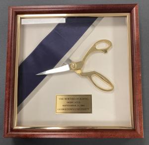 Gold handled scissors and ribbon in a wooden display case