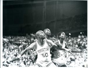 B X W photo of two Georgetown basketball players -- Michael Graham and Reggie Williams -- blocking out opposing player, arms outstretched, to position themselves for a rebound