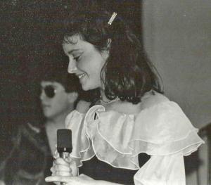 Picture of singer wearing a white ruffled dress holding a microphone