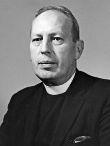 James Horigan, a middle aged priest with short hair wearing a dark coat and a tall white collar