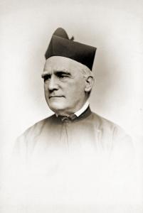 Soft vignette photograph of James Ward, an older man with short gray hair, wearing dark robes, a white collar, and a Jesuit biretta