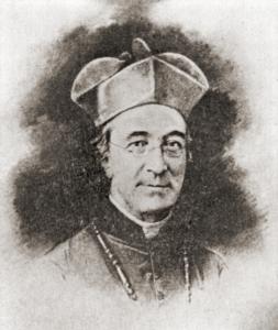 James Van de Velde, an older man with glasses wearing a Jesuit biretta, dark robes, and white collar
