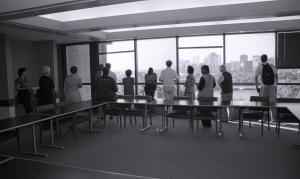 Black and white photograph showing the backs of Library staff standing at the windows of the Murray Room looking out toward the Pentagon